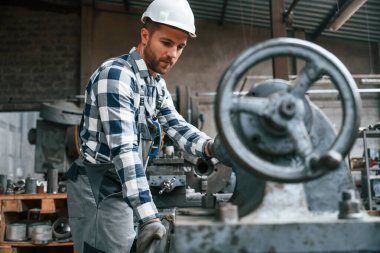 Üniformalı fabrika çalışanı içeride. Endüstri makinesiyle.