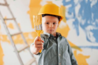 Arkasında mavi ve sarı renkler var. Ukrayna ve barış kavramı. Küçük çocuk ev odasında duvarları boyuyor..