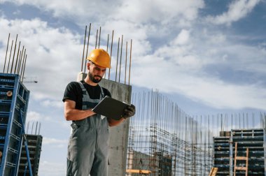 Sürecin kontrolü. Foreman belgelerle birlikte. Üniformalı adam inşaat alanında çalışıyor..