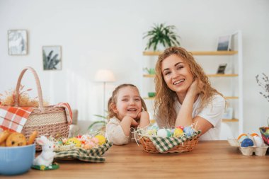 Gülümsüyor ve eğleniyor. Mutlu anne ve kız Paskalya tatillerini birlikte kutluyor..