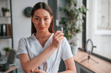 Aşı kavramı. Elinde şırıngayla. Beyaz önlüklü güzel bayan doktor ofiste..