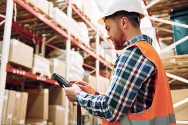 Tableti ellerimde tutuyorum. Üniformalı eleman gündüz vakti depoda çalışıyor..