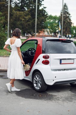 Beyaz ve kırmızı renkli bir arabada oturuyorlar. Gelinler evlenmeden önce dışarıda olurlar..