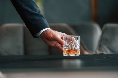 Masadan bir bardak alkollü içecek alan adamın elini kapat..
