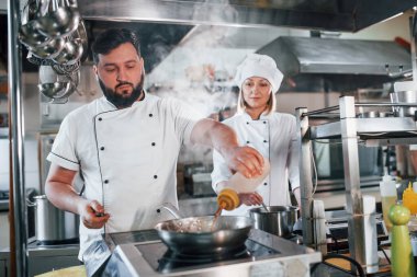 Kadın ve erkek birlikte uyanıyorlar. Profesyonel aşçı mutfakta yemek hazırlıyor..