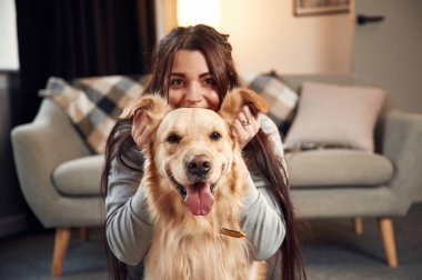 Kulaklarımla, önümle, portremle oynuyorum. Kadın Golden Retriever köpeğiyle evde..