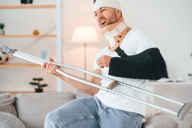 Ayakta duruyor, koltuk değneğini tutuyor ve gitar çalıyormuş gibi yapıyor. Eğleniyorum. Evdeki adam içeride. Yaralı..