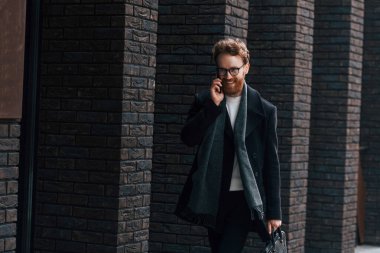 Telefonla konuşuyorum. Sakallı ve gözlüklü şık adam binanın yanında..