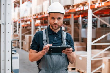 Rafların yanında yürüyorum. Üniformalı eleman gündüz vakti depoda çalışıyor..