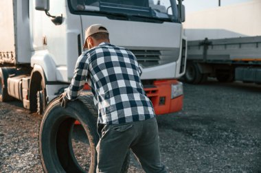 Tekerleklerle çalışmak. Genç kamyon şoförü gündüz vakti aracıyla geliyor..