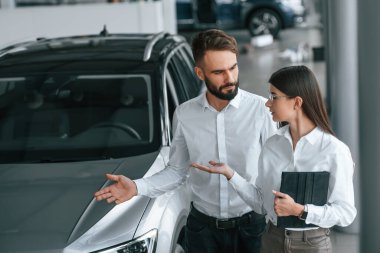 Yürüyor ve otomobili seyrediyor. Beyaz elbiseli bir adam araba galerisinde birlikte..
