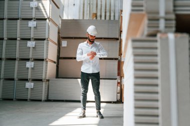 Resmi kıyafetler içinde ciddi bir yönetici. Depo işçisi depoda bir sürü ürünle birlikte..