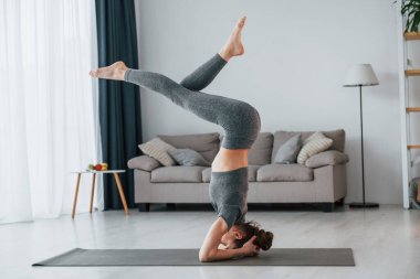 Amuda kalkmak. İnce vücutlu ve yoga elbiseli genç bir kadın evde..