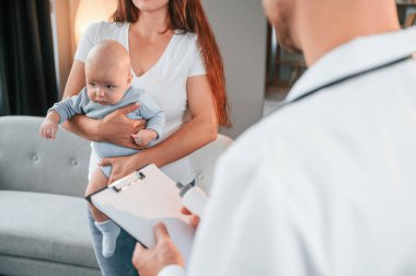 Reçeteli. Erkek doktor, kadının yeni doğan bebeğine evde bakıyor..
