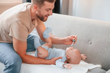 Pipetle ilaç veriyor. Yeni doğmuş bebeğiyle baba içeride. Bekar baba kavramı.