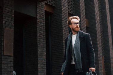 Binanın yakınında yürüyorum. Sakallı ve gözlüklü şık adam dışarıda..