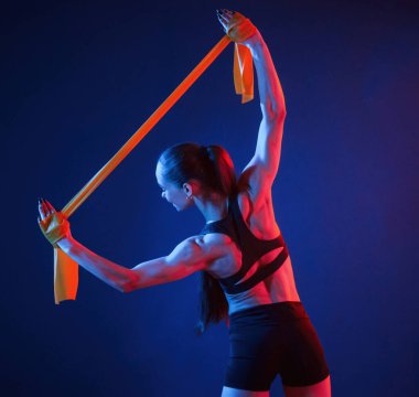 Koli bandını elimde tutuyorum. Güzel kaslı kadın stüdyoda neon ışıklı..