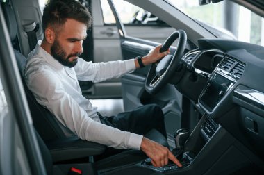 Otomobilin salonunu inceliyorum. Beyaz elbiseli genç adam araba galerisinde..