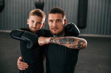 Beginning of the professional sport. Coach is teaching the boy box techniques indoors. clipart