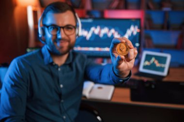 Bitcoin 'i tutuyorum. Hisse senedi tüccarı kapalı alanda bilgisayar başında çalışıyor. Değişim ve para kavramı.
