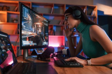 Yan görüş. Genç, güzel bayan oyuncu tetikçiyi oynuyor. Neon ışıkları.