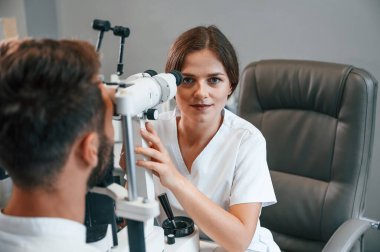 Özel optometrist cihaz kullanarak klinikteki kadın doktor tarafından erkeğin görüşü kontrol edildi..