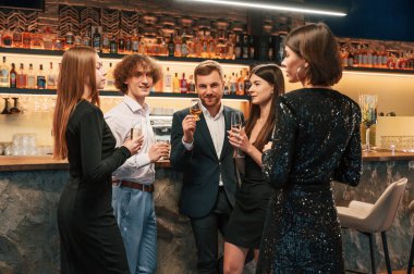 Konuşmak, gülümsemek, eğlenmek. Güzel giyinmiş bir grup insan içeride yeni yılı kutluyorlar..