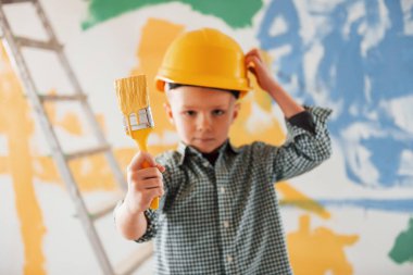 Arkasında mavi ve sarı renkler var. Ukrayna ve barış kavramı. Küçük çocuk ev odasında duvarları boyuyor..