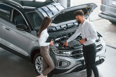 Kaput açıldı. Beyaz elbiseli bir adam araba galerisinde birlikte..