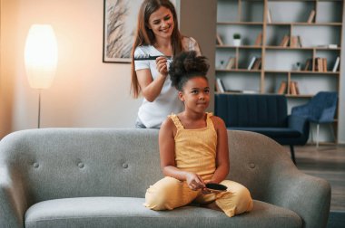 Saçımı kestiriyorum. Genç anne kızıyla birlikte dairede..