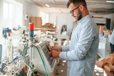 Makine operatörü bir cihaz kurmakla meşgul. Beyaz elbiseli matbaacı içeride..