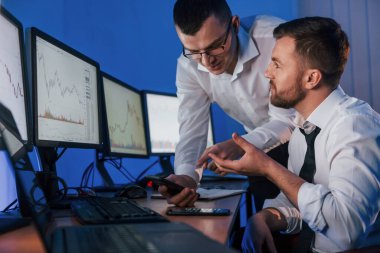 Kâr etmek. Ofiste değişim teknolojisiyle çalışan iki borsacı..