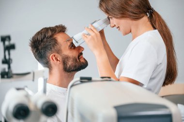 Modern teknolojiler. Özel optometrist cihaz kullanarak klinikteki kadın doktor tarafından erkeğin görüşü kontrol edildi..