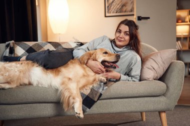 Birlikte kanepede uzanıyorduk. Kadın Golden Retriever köpeğiyle evde..