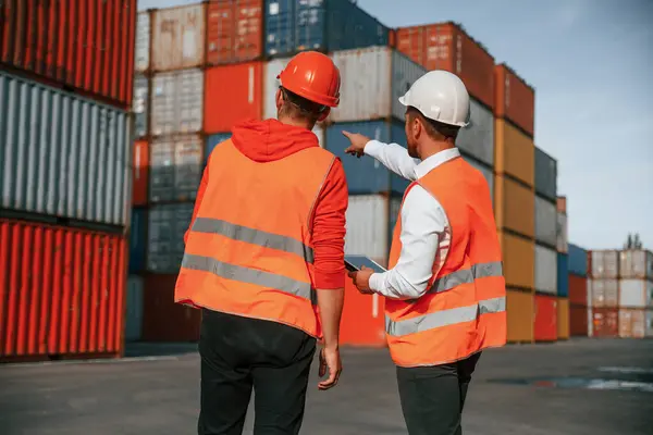 stock image Showing the objects. Two male workers is on the location with containers.