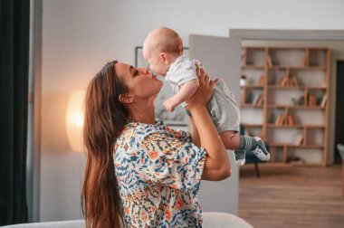 Çocuğu ellerinde tutarak. Güzel mutlu anne ve yeni doğan oğlu evde..