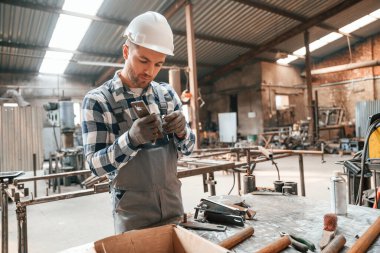 Profesyonel aletleri kullanarak. Üniformalı fabrika çalışanı içeride..