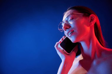 Telefonla konuşuyorum. İçerideki neon ışıkta duran genç bir kadının portresi..