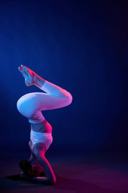 Kafa standı yapıyorum. Spor elbiseli genç bayan stüdyoda neon ışıklarıyla bekliyor..