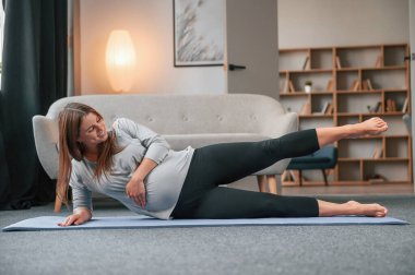 Yoga egzersizleri yapıyorum. Güzel hamile kadın evde..
