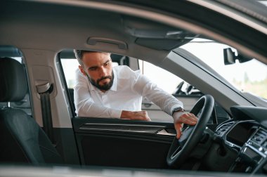 Otomobilin içine bakıyorum. Beyaz elbiseli genç adam araba galerisinde..