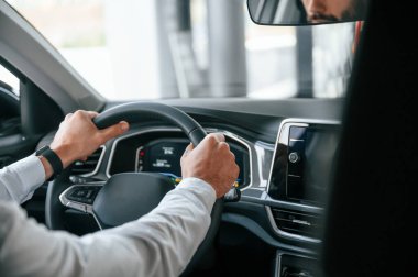 Test sürüşü. Beyaz elbiseli genç adam araba galerisinde..