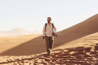 Fotografik ekipmanlarla. Günlük giysiler içindeki erkek turist Afrika çöllerinde, Namibya 'da..