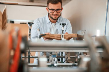 Kesme makinesini kullanarak. Beyaz elbiseli matbaacı içeride..