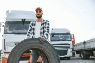Hasarlı lastiği tutuyorum. Genç kamyon şoförü gündüz vakti aracıyla geliyor..