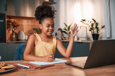 Çevrimiçi çalışma. Gündüz vakti evde rahat giyinen sevimli siyah kız var..