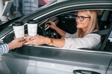 Bir bardak içki içiyorum. Beyaz elbiseli kadın araba galerisinde..