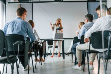Elinde not defteri olan kadın yüksek lisans yapıyor. Profesyonel iş adamlarından oluşan bir grup ofiste..