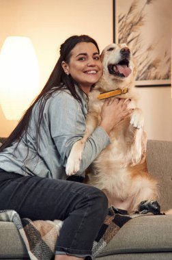 Kanepede oturuyordum. Kadın Golden Retriever köpeğiyle evde..