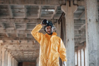 Gaz maskesini çıkarıyorum. Kıyamet sonrası binanın harabelerinde kimyasal koruma kıyafeti giymiş bir adam..